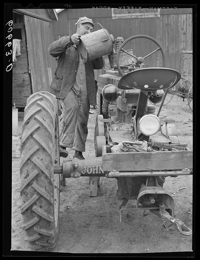 Pouring water in tractor before starting out to plow. Grundy County, Iowa
