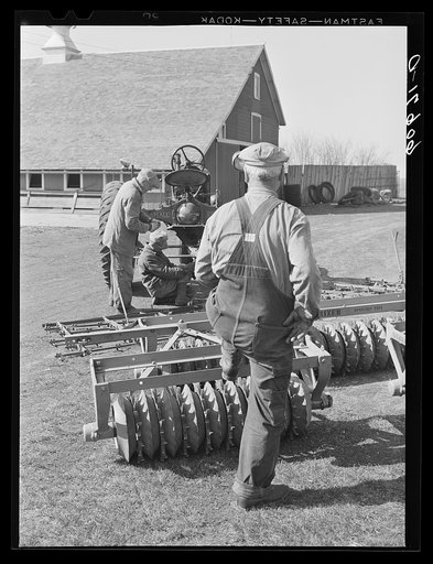 Fred Coulter, Iowa corn farmer, watching hired men adjust harrow onto tractor. Grundy County, Iowa