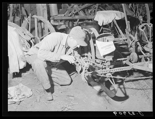 Checking the corn planter to see that it drops three kernels each time the wire is tripped before beginning planting operations. Grundy County, Iowa