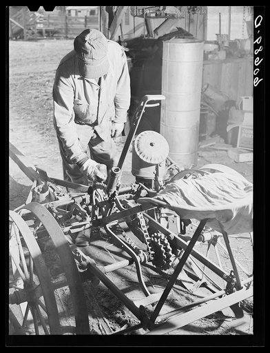 Oiling corn planter in machine shed before beginning planting operations. Grundy County, Iowa