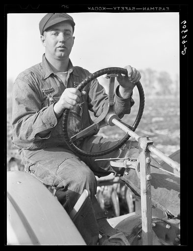 Iowa farm boy at tractor wheel. Harrison County, Iowa