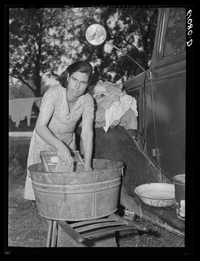 Mother of migrant fruit picking family doing family wash in roadside camp where fifteen farmers are living. Berrien County, Michigan