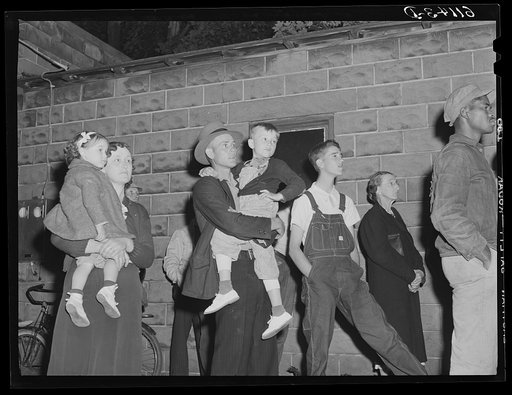 Migrant fruit workers watching open air movie given by local merchants who remain open for business. Millburg, Michigan