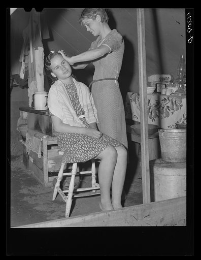Migrant girl fixing her sister's hair. Roadside camp of fruit worker. Berrien County, Michigan