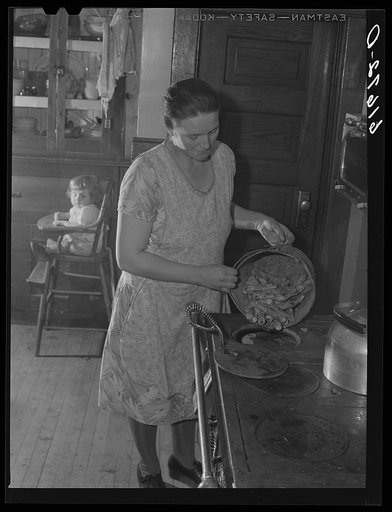 Mrs. Bettenhausen using corn cobs for fuel. McIntosh County, North Dakota