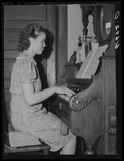 Farm girl playing organ in home. McIntosh County, North Dakota