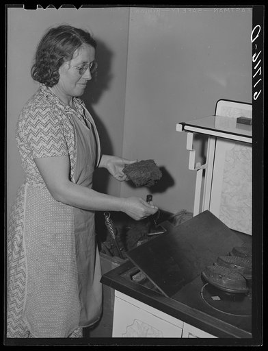 Farm woman putting "barnyard lignite" in kitchen stove. McIntosh County, North Dakota