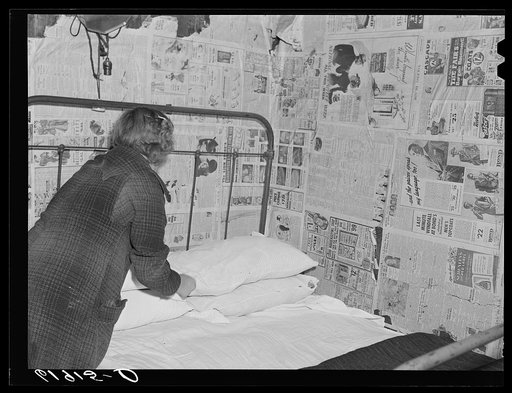Daughter of day laborer making bed. Family of six sleeps in this one room, two beds. Scioto Marshes, Hardin County, Ohio
