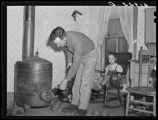 Rehabilitation borrower putting log in stove. Labette County, Kansas