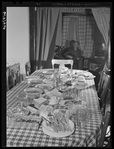Dinner table after dinner at Mrs. Jones's boardinghouse. Sixteen men live here. Men in background sitting in parlor after dinner. Radford, Virginia