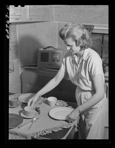 Wife of defense worker setting table for dinner in trailer home. Trailer camp at Erie, Pennsylvania