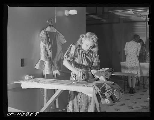 Wife of defense worker ironing clothes in utility building at FSA (Farm Security Administration) trailer camp. Erie, Pennsylvania