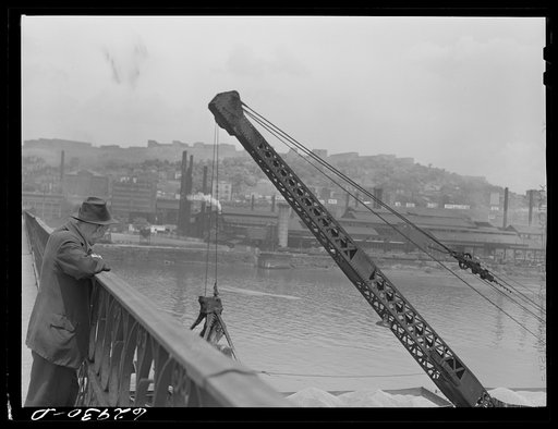 Man watching steamshovel unload sand from barges. Pittsburgh, Pennsylvania
