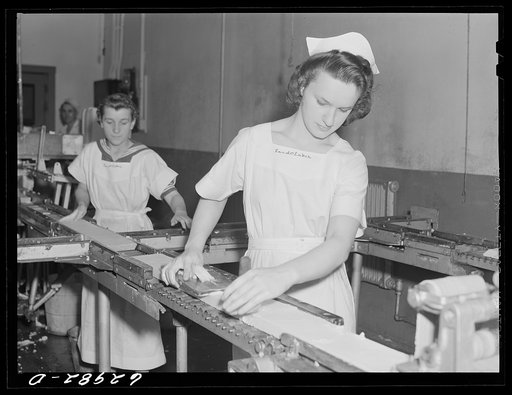 Butter going through machine which cuts it into quarter-pound sections. Land O'Lakes plant, Chicago, Illinois