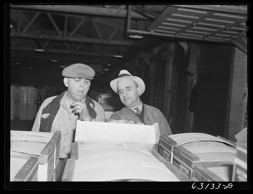 Commission merchant examining produce at fruit warehouse. Chicago, Illinois