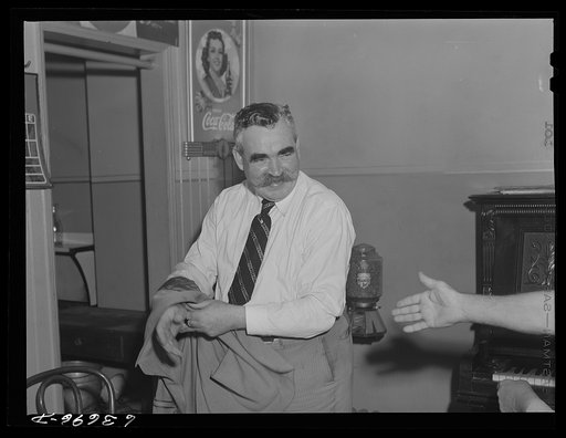 Jack Dwyer taking off his coat in a saloon. Detroit, Michigan