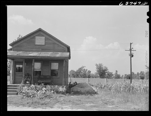 House in Negro section, Detroit, Michigan. Concrete wall in background is one half mile long, and serves to separate Negro section from white subdivision