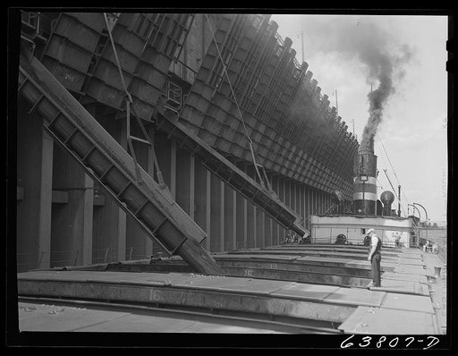 Loading iron ore into hold of boat. First mate directing operations. Allouez, Wisconsin