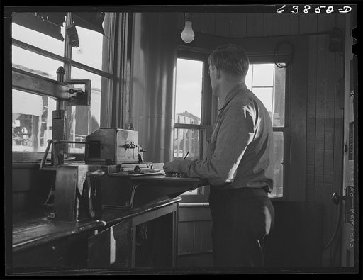 In the scale house, weighing cars of ore as they pass over the scales at the rate of three and a half a minute. Great Northern Railroad yards, Superior, Wisconsin