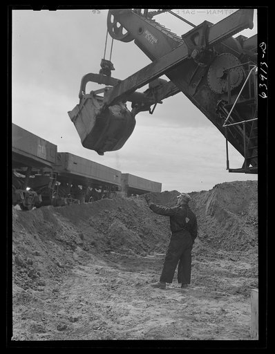 Electric power shovels scoop up iron ore; eight cubic yards per shovelful. Albany Mine near Bovey, Minnesota