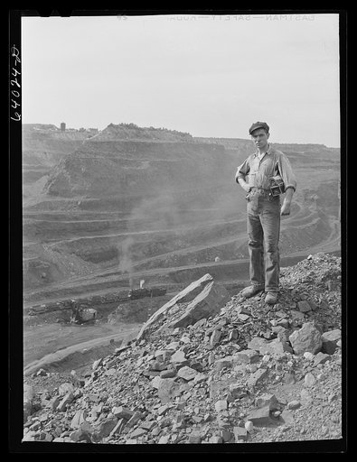 One end of the Hull-Rust-Mahoning pit, largest open pit iron mine in the world, near Hibbing, Minnesota. The pit is two and a half miles long, three quarters of a  mile wide and about four hundred feet deep