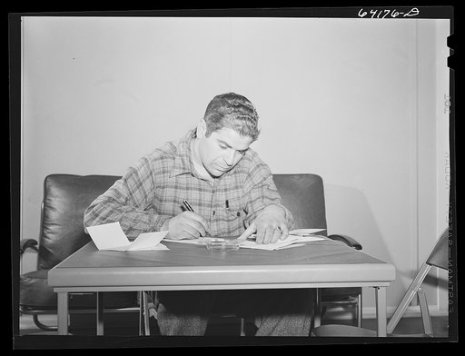 Defense worker writing a letter home in lobby of one of the FSA (Farm Security Administration) dormitories for defense workers. Aberdeen, Maryland