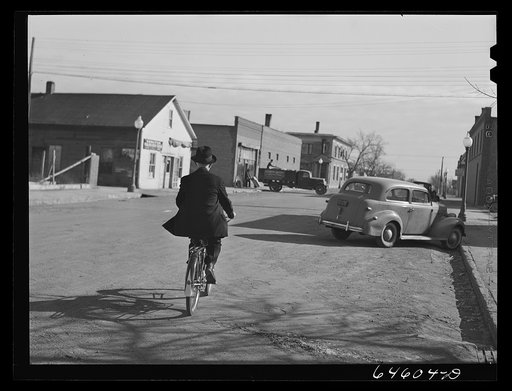 Ipswich, South Dakota. Village priest riding a bicycle to town