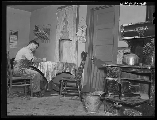 Adams County, North Dakota. North Dakota stock farmer, George P. Moeller, writing a letter at the kitchen table