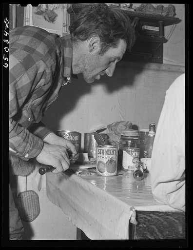 Garfield County, Montana. Sheepherder opening cans for supper in his winter quarters