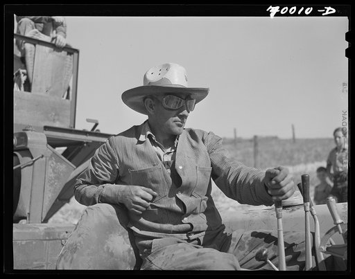 Driver of caterpillar tractor which draws combine in wheat fields of Whitman County, Washington
