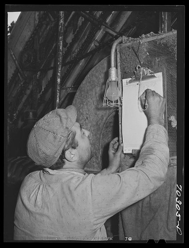 Weigher marking up weight of sacks of green hops picked by portable-type mechnical hop picker. Yakima County, Washington