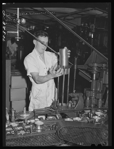 Feeding lids to machine which also seals the cans of salmon. Columbia River Packing Association. Astoria, Oregon