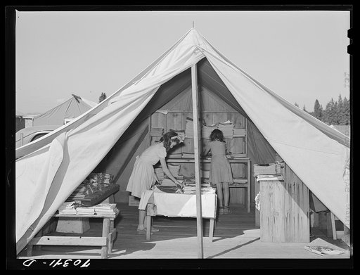 Library tent at the FSA (Farm Security Administration) mobile camp for migratory farm workers. Odell, Oregon. The girls working in the library receive credit in the Junior Campers League for work in the library