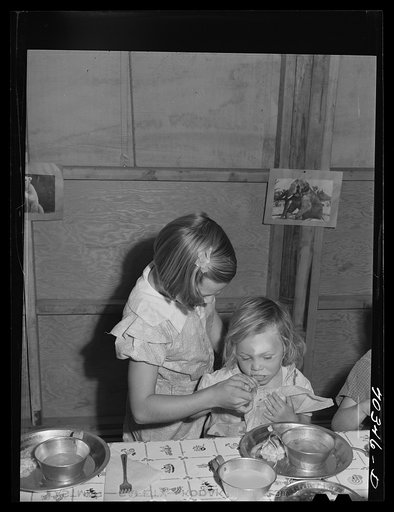 Lunch at the nursery school at the FSA (Farm Security Administration) mobile camp for migratory farm workers. Odell, Oregon. The older girl, member of the Junior Campers League, receives credits for helping in the nursery school