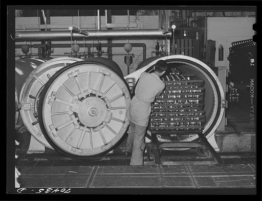 Putting trays of canned salmon into ovens for cooking. Columbia River Packing Association, Astoria, Oregon