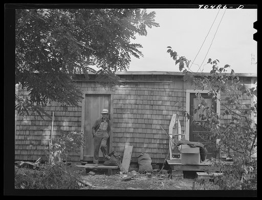 Workman at Umatilla ordnance depot, in front of house which is a converted woodshed and which he shares with another workman. Hermiston, Oregon
