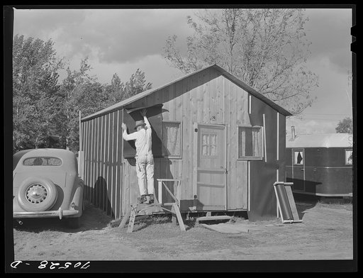 Cabin court owners putting up tar paper siding in preparation for winter weather. Hermiston, Oregon