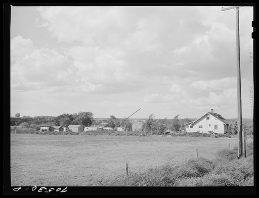 Trailers and other forms of temporary housing for workmen at the Umatilla ordnance depot ground near a farmhouse. Hermiston, Oregon. Workmen at the depot established temporary housing near sources of water