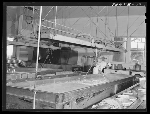 Tillamook cheese plant. Tillamook County, Oregon. A lactic ferment starter is added when the milk is poured into these 10,000 pound stainless steel vats. Worker is testing acidity of curdling milk