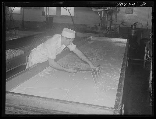 Untitled photo, possibly related to: Breaking up curdling milk is one of the first steps of cheesemaking. Tillamook cheese plant, Tillamook, Oregon. This also distributes evenly the lactic ferment starter