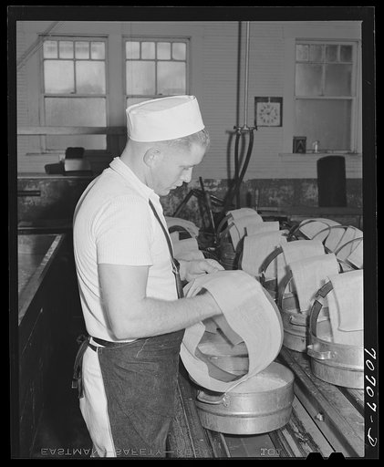 Putting cheesecloth on molds in which the cheese will be pressed. Tillamook cheese plant, Tillamook County, Oregon