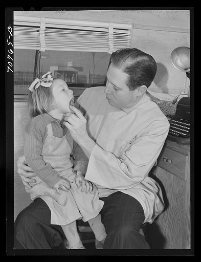 FSA (Farm Security Administration) dentist looking at the teeth of a young migrant child who lives at the FSA camp for farm families at Caldwell, Idaho