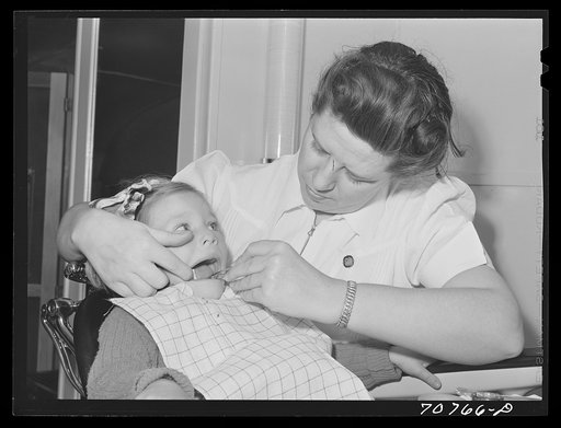 Untitled photo, possibly related to: FSA (Farm Security Administration) nurse examines the teeth of migrant in the FSA dental trailer at the FSA camp for farm workers. Caldwell, Idaho