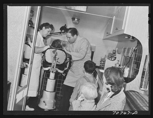 FSA (Farm Security Administration) dentist and migrant child in the FSA dental trailer at the FSA camp for farm families. Caldwell, Idaho