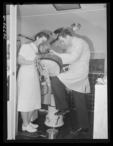 FSA (Farm Security Administration) dentist and nurse with migrant child in the FSA dental trailer at the FSA camp for farm families. Caldwell, Idaho