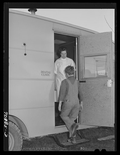 The FSA (Farm Security Administration) nurse welcomes migrant boy to FSA dental trailer at the FSA camp for farm families. Caldwell, Idaho