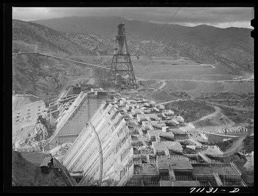 Shasta Dam under construction. Cable cars carrying materials operate from the high tower. Shasta County, California