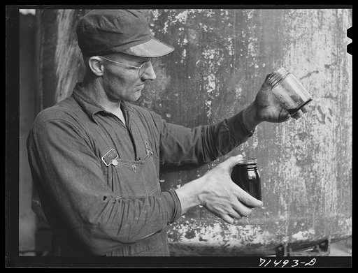 Workman with samples of "soap" oil made from olives. The "soap" oil is a thick, dark green oil. Strathmore, California