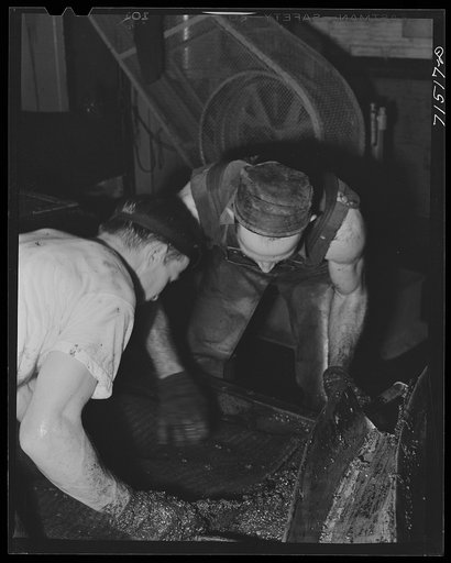 Untitled photo, possibly related to: Workmen put crushed olives into heavy bags which will be put under hydraulic pressure to extract the oil. It takes an average of fifty-six pounds of olives to make a gallon of oil. Lindsay, California