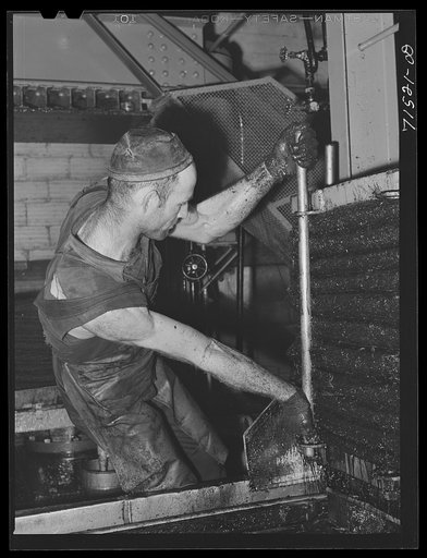 Putting bars up to hold bags of olive pulp in place while under the hydraulic pressure which forces out the oil. Lindsay, California. About seventy-five percent of the oil content of the olives is removed by the first application of pressure; it is the oil obtained in the first pressing which is ter
